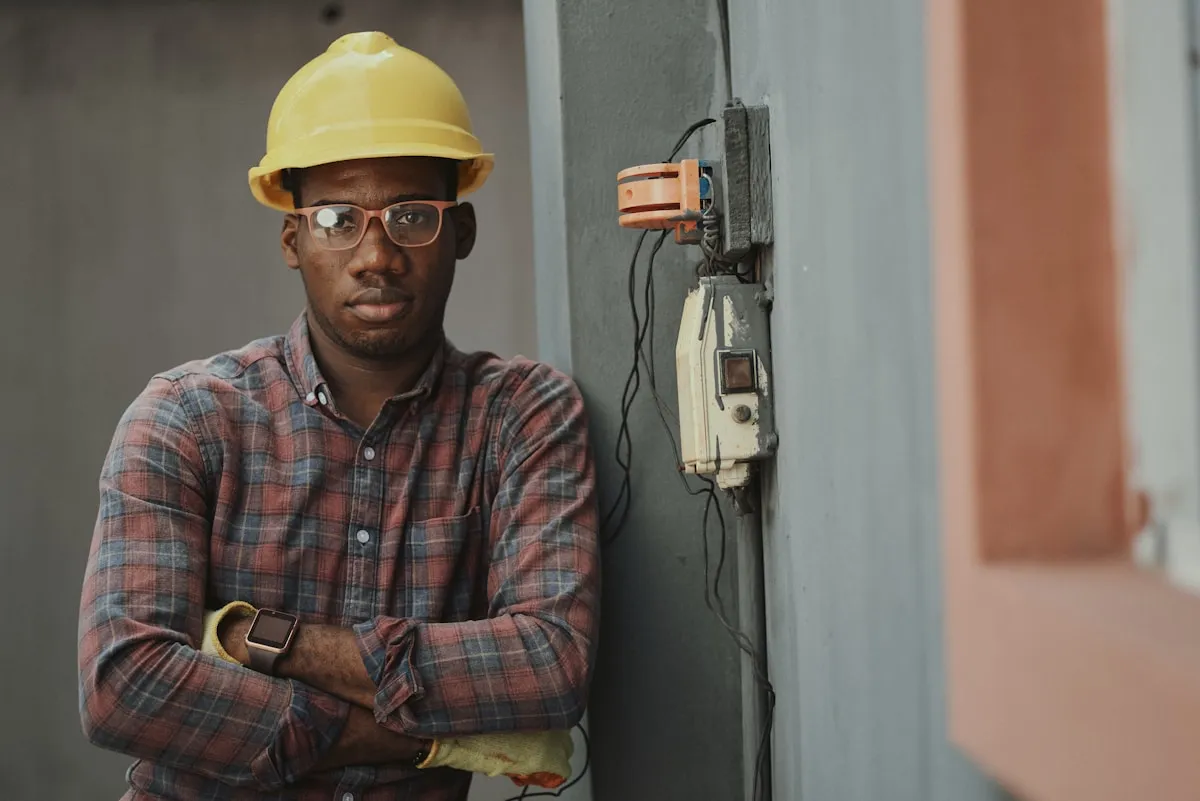 Contractor in hard hat and safety vest checking phone on construction site